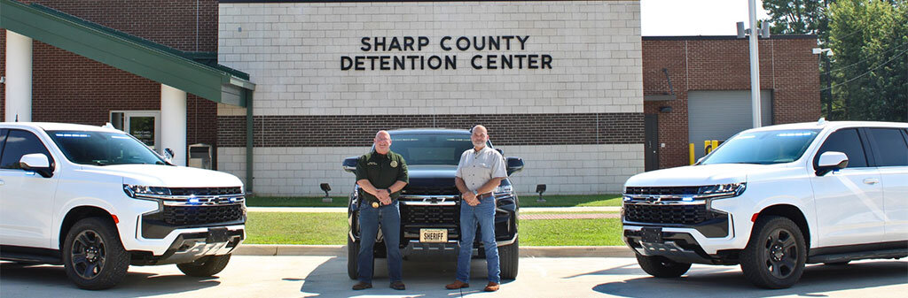 The sheriff and a deputy with three Sharp County Sheriff Patrol vehicles in front of the Detention Center.